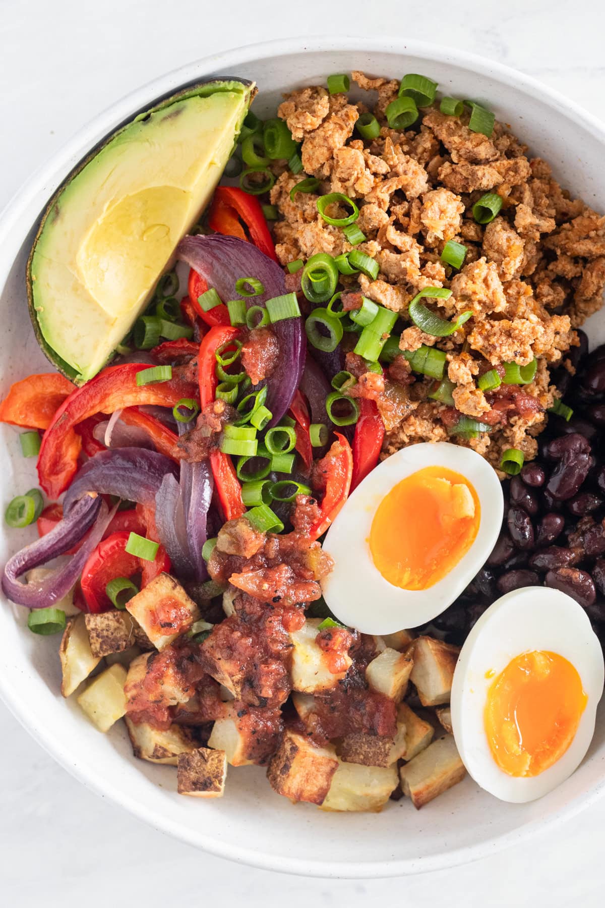 Bowl with potatoes, veggies, eggs and beans.