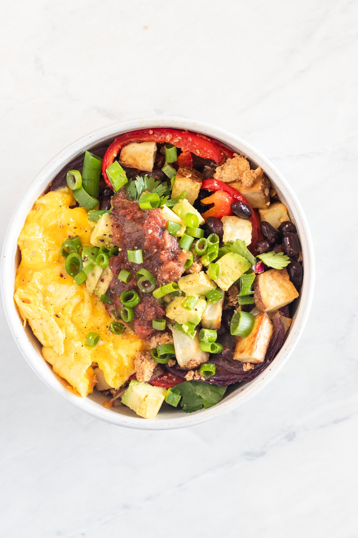 Breakfast burrito bowl with eggs and potatoes topped salsa.