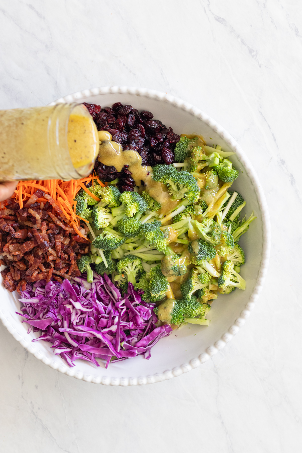 Ingredients for a broccoli crunch salad in a white bowl.