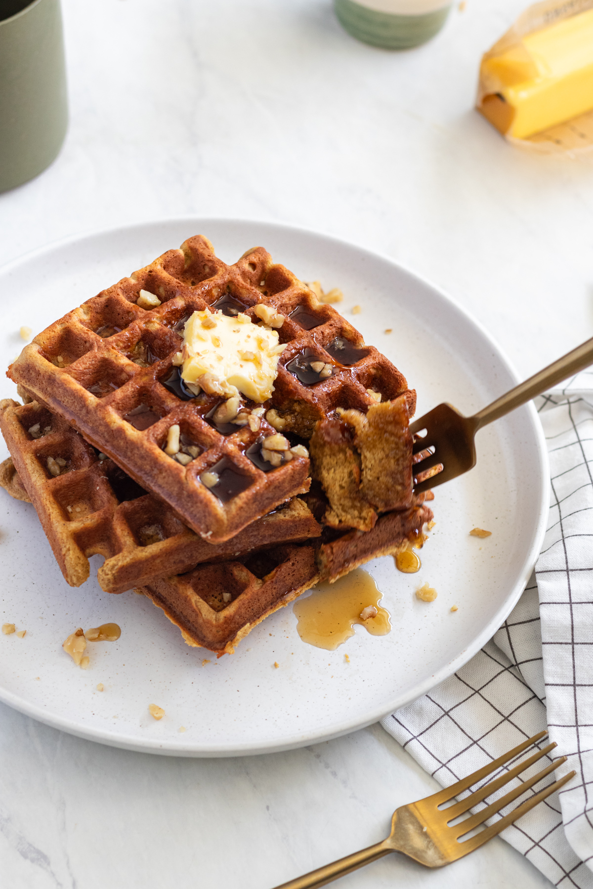Fork in a stack of pumpkin waffles on a white plate.
