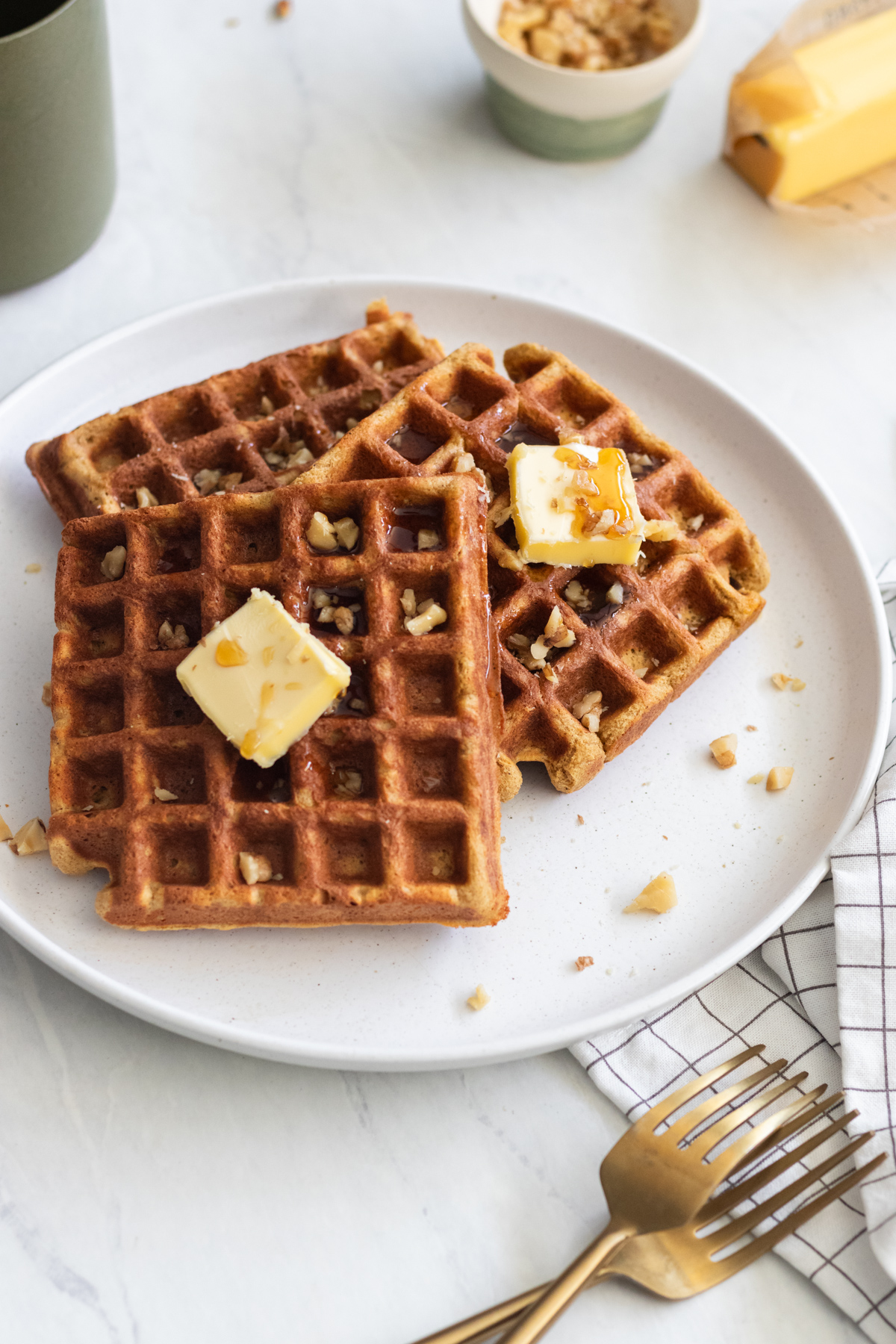Plate with 3 gluten free pumpkin waffles topped with butter and maple syrup.