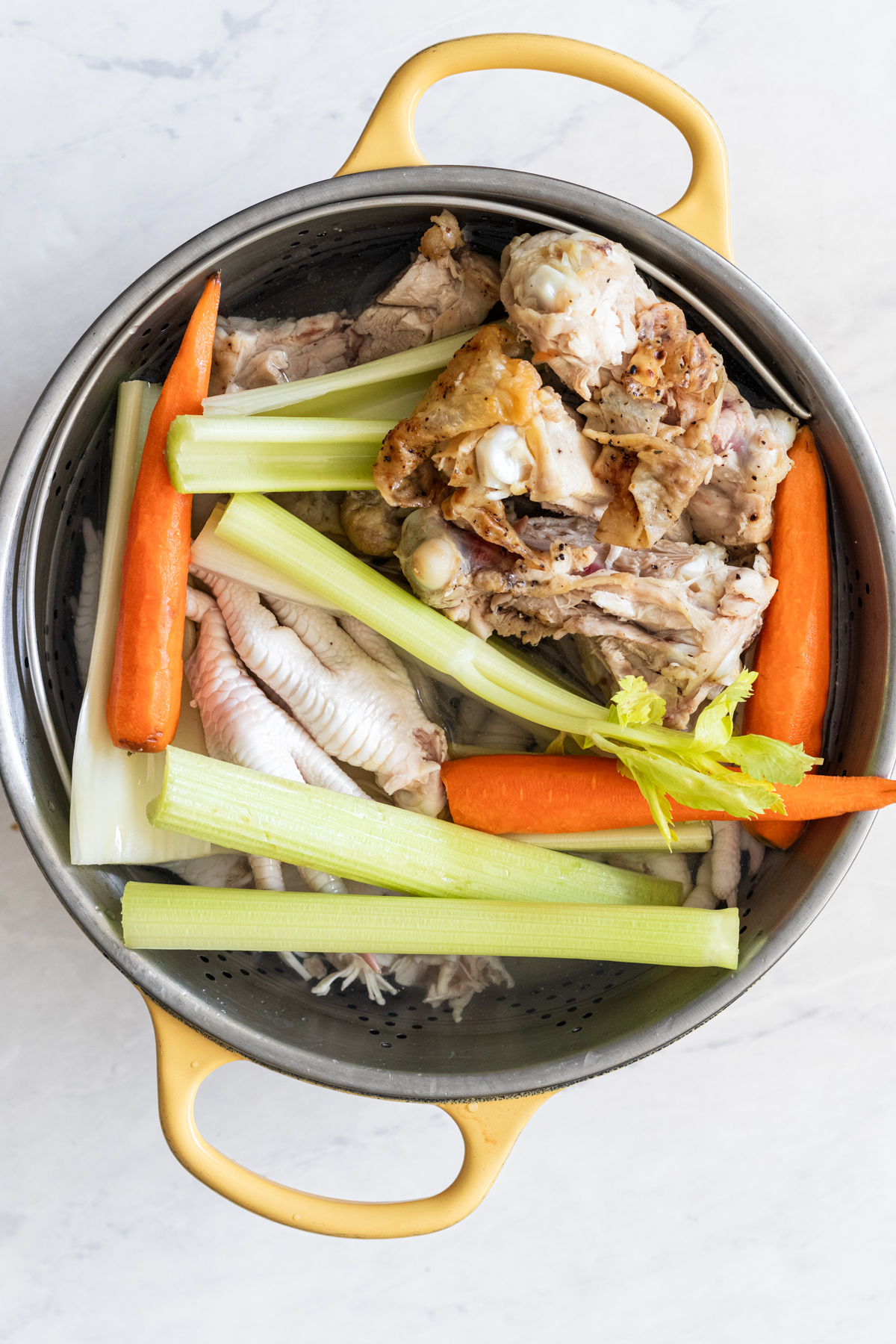 Uncooked celery, carrots and bones in a large pot.