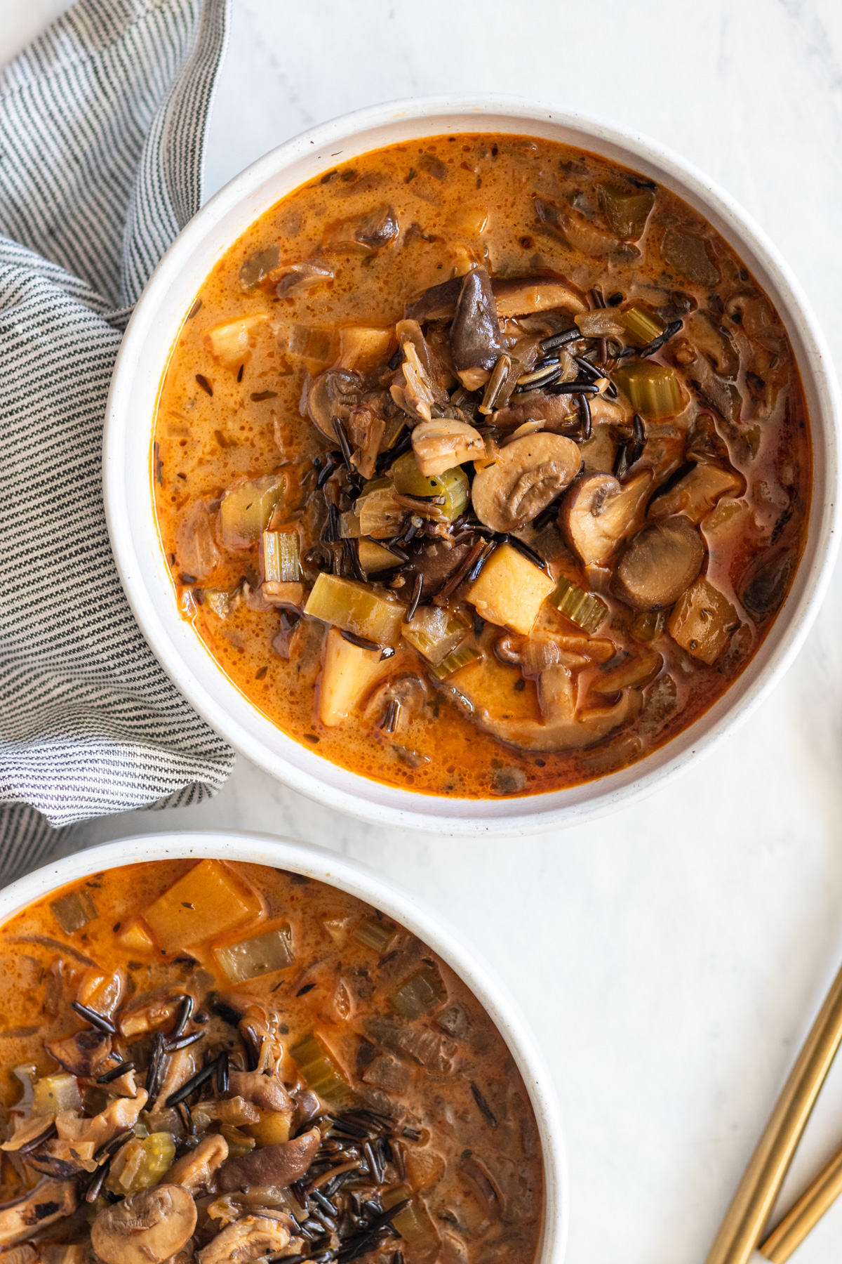 Two white bowls with cream of mushroom wild rice soup.
