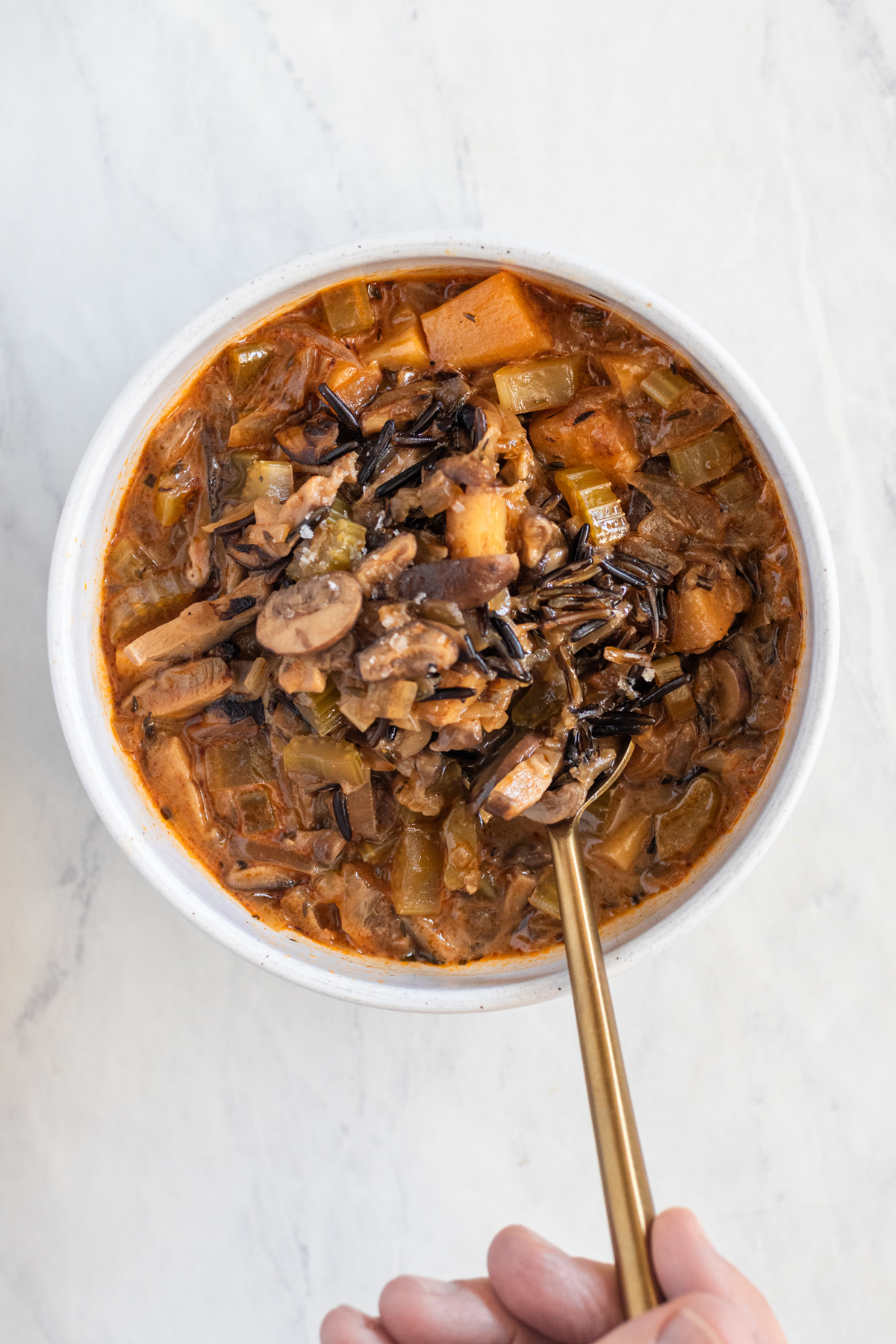 A bowl with mushroom and rice soup and a spoon in it.