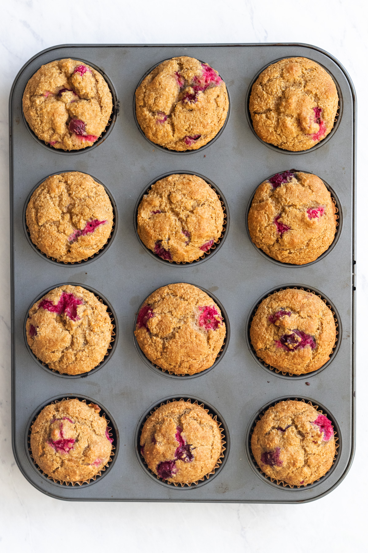 Cranberry orange muffins in a muffin pan.